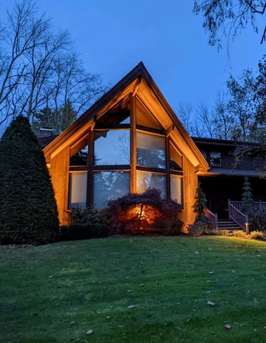 Beautifully lit A-frame home with professional outdoor lighting at dusk