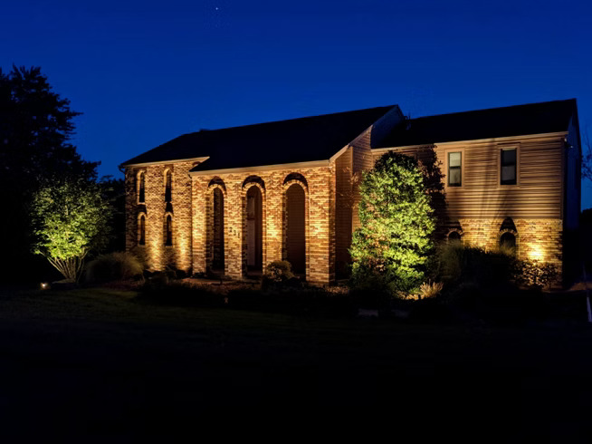 Professional landscape lighting on Pittsburgh brick home with architectural uplighting