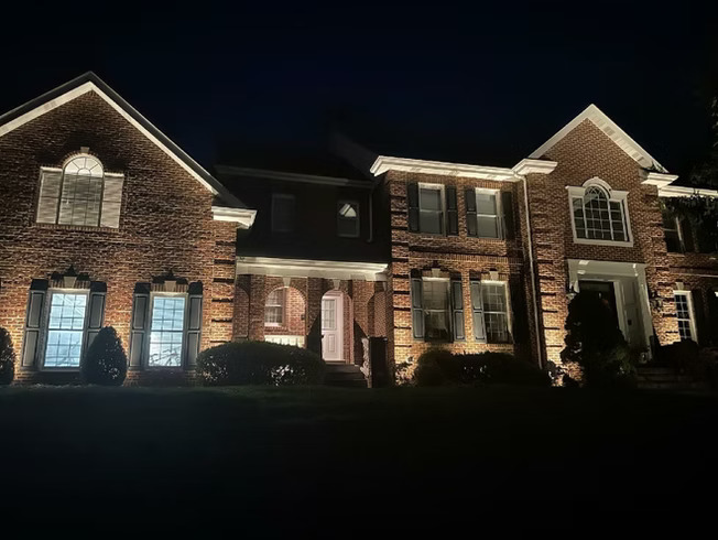Large brick colonial home with warm outdoor lighting